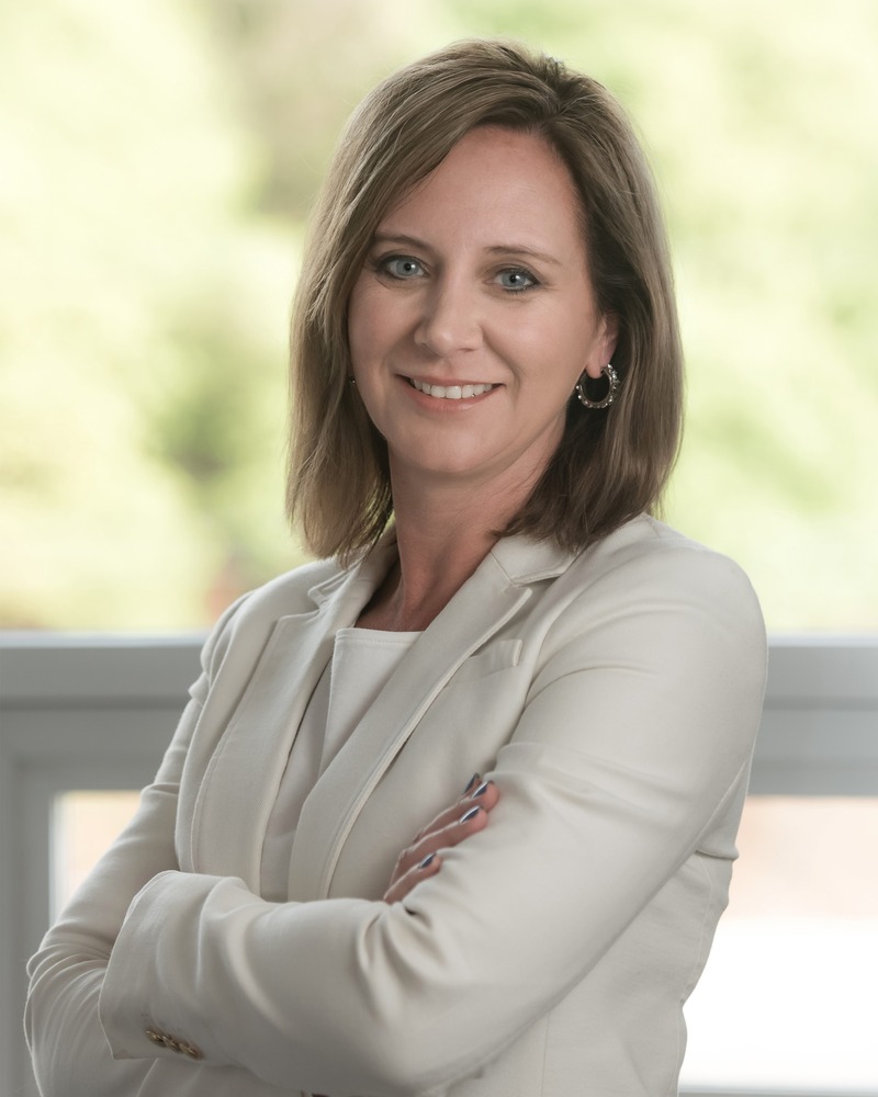 A photo of partner Ginny O'Connor smiling with her arms crossed.