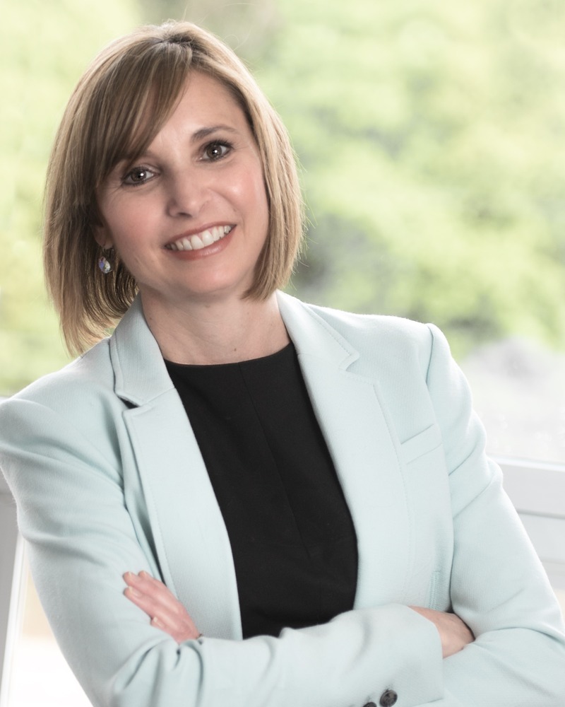 A photo of partner Jennifer Barrett smiling with her arms crossed.